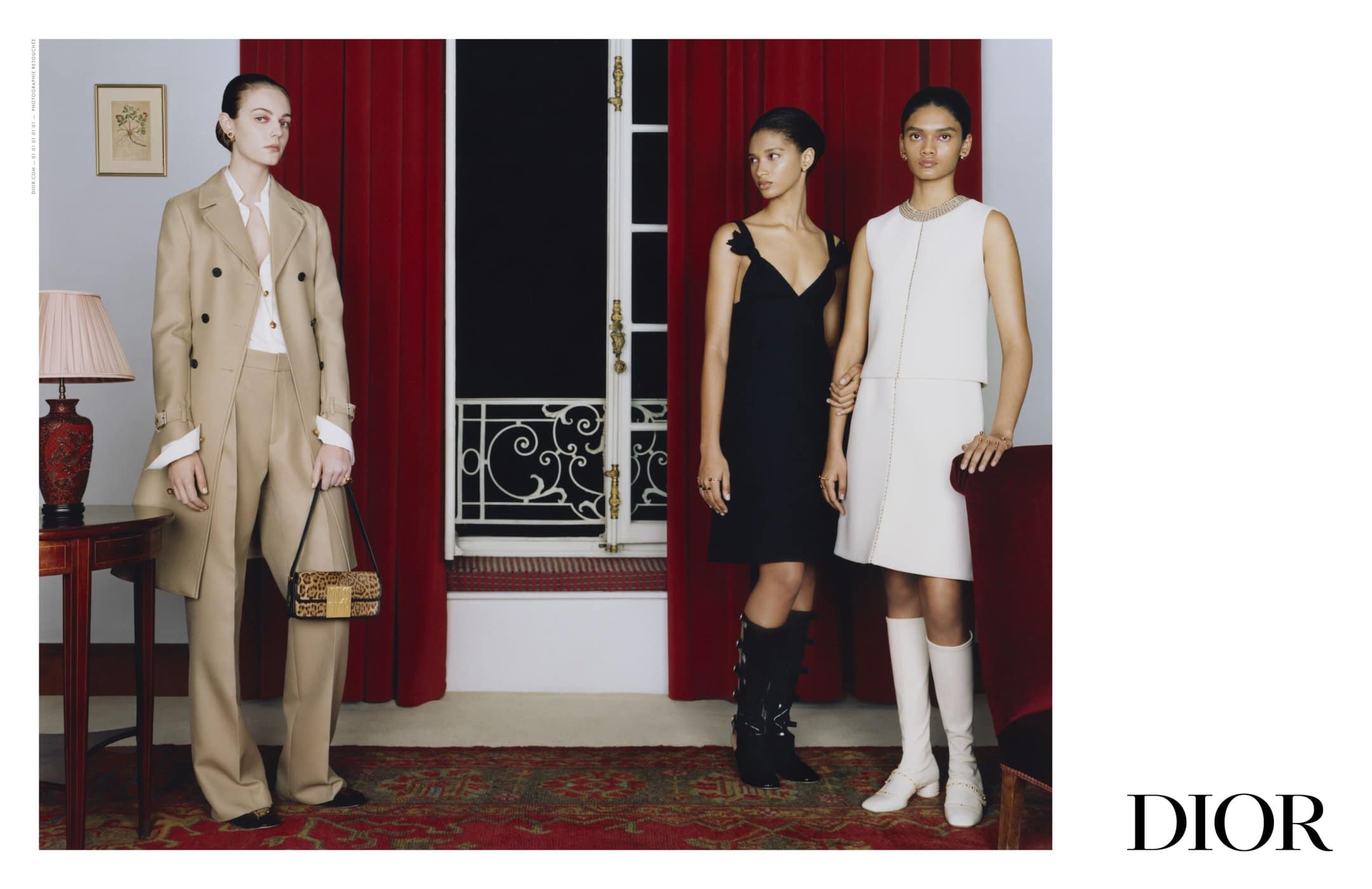 Three women are posing indoors in a fashion editorial shot, wearing dresses and a pantsuit with a leopard-print handbag, styled in neutral tones.