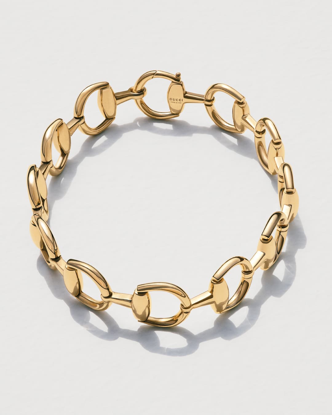 Close-up of a gold Gucci horsebit chain bracelet on a white background, showcasing its design, materials, and craftsmanship in detail.