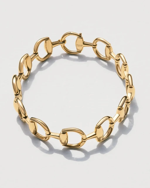 Close-up of a gold Gucci horsebit chain bracelet on a white background, showcasing its design, materials, and craftsmanship in detail.