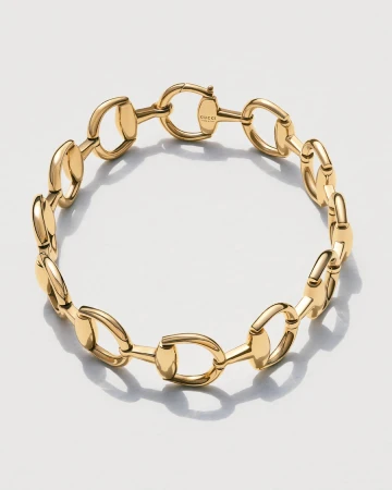 Close-up of a gold Gucci horsebit chain bracelet on a white background, showcasing its design, materials, and craftsmanship in detail.