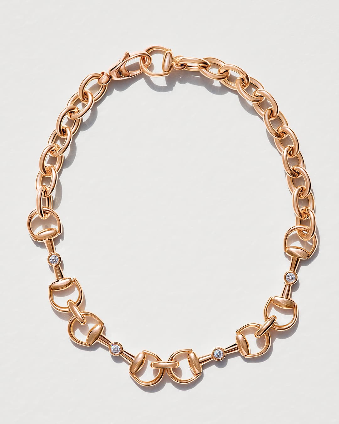 Elegant gold chain necklace with a horsebit design and sparkling gem accents, beautifully isolated on a clean, bright white background.