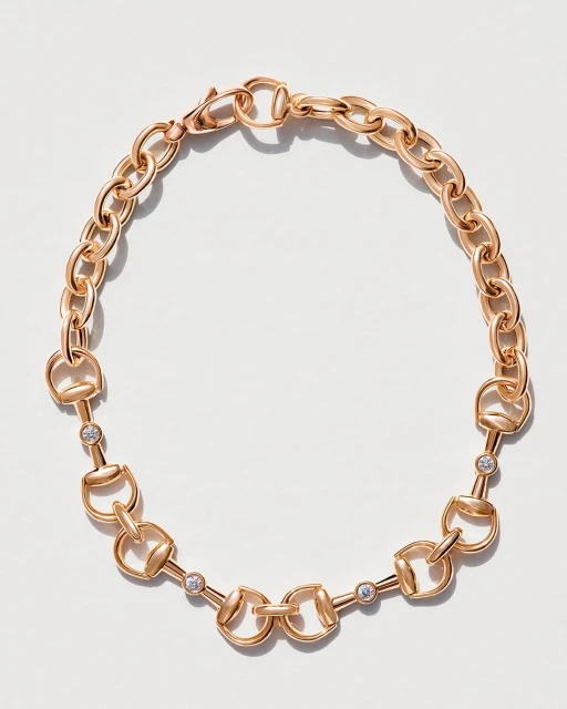 Elegant gold chain necklace with a horsebit design and sparkling gem accents, beautifully isolated on a clean, bright white background.
