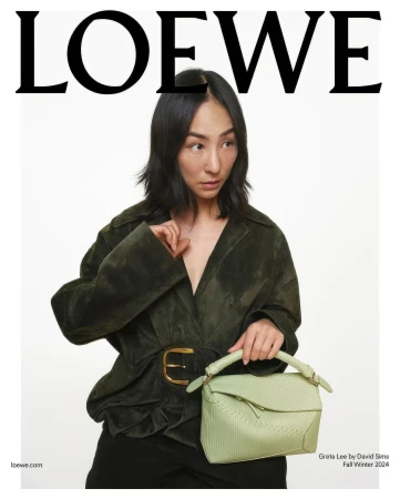 Fashion editorial featuring an Asian female model in a green jacket and black pants, holding a light green handbag against a white backdrop.