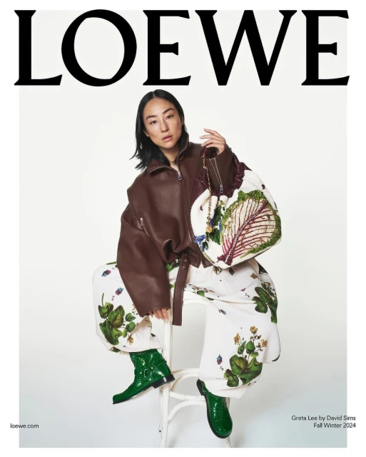 Fashion editorial cover featuring a woman in a brown leather jacket and patterned pants, holding a cabbage-print handbag on a white background.