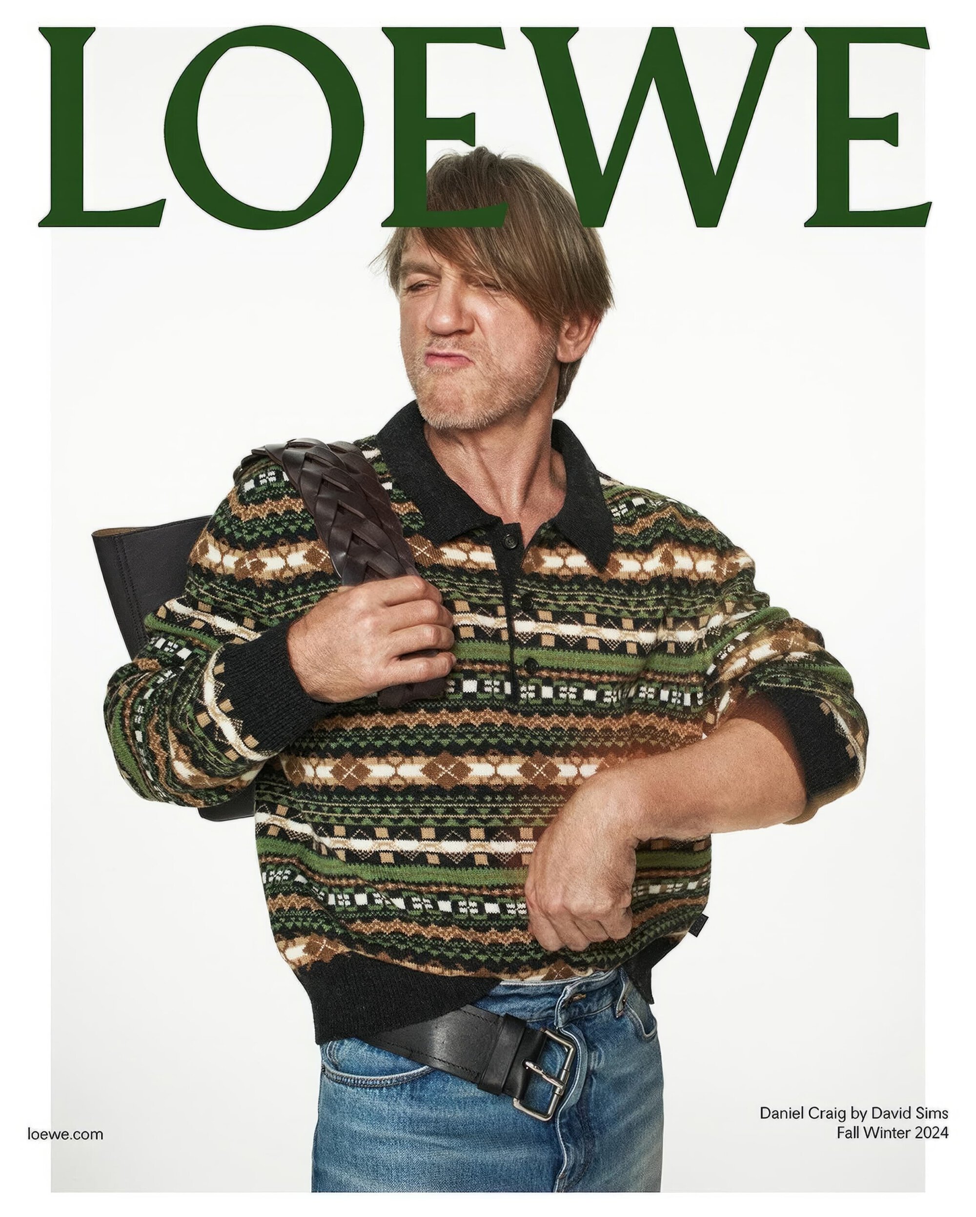 Daniel Craig stars in a Loewe fashion campaign, wearing a patterned sweater and jeans, carrying a brown woven leather bag.