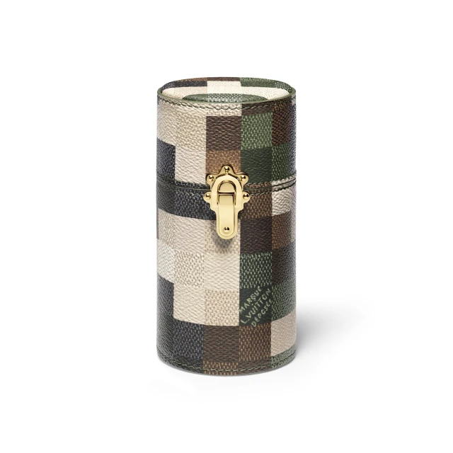 Cylindrical Louis Vuitton box with Damier-patterned leather, featuring a gold clasp, photographed against a solid white backdrop in a studio setting.