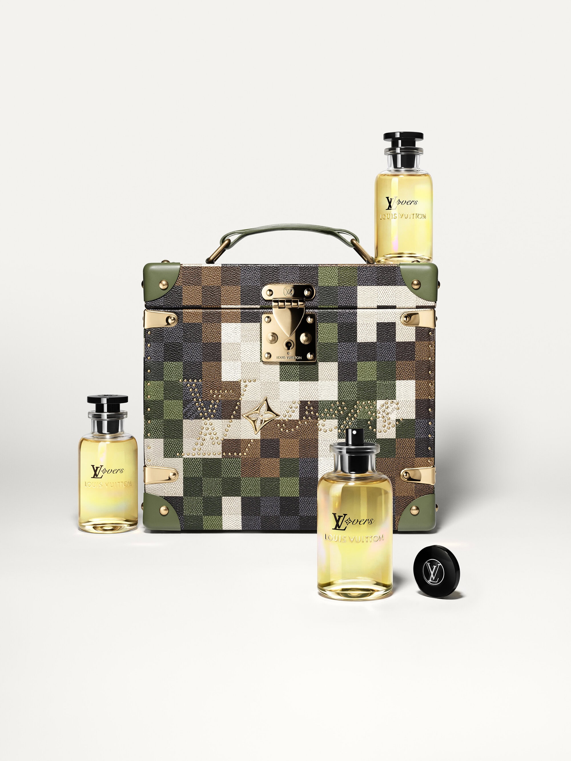 Four Louis Vuitton fragrance bottles with black caps are arranged around a luxury travel case against a white backdrop.