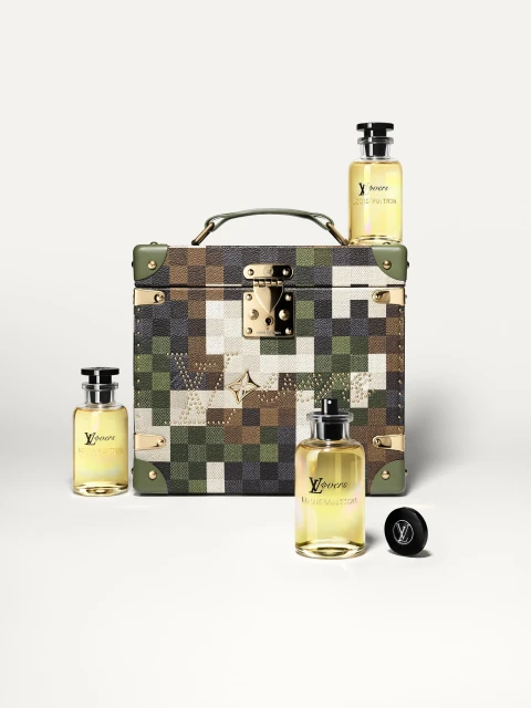 Four Louis Vuitton fragrance bottles with black caps are arranged around a luxury travel case against a white backdrop.
