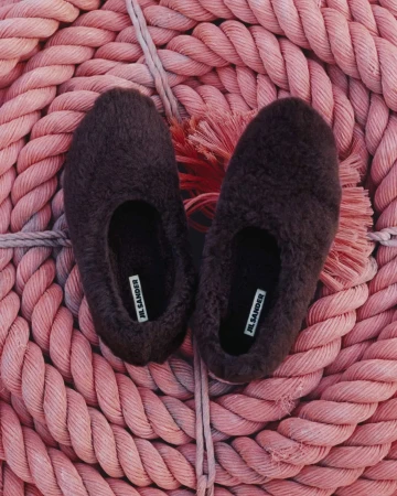 Close-up shot of brown, furry Jil Sander slippers on a pink rope background. Fashion product photography with minimalist aesthetic.