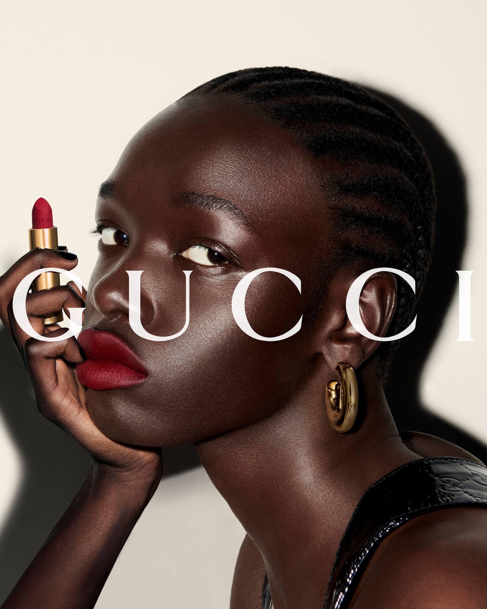 Close-up portrait of a Black woman holding a red lipstick against a plain white background for a Gucci ad campaign