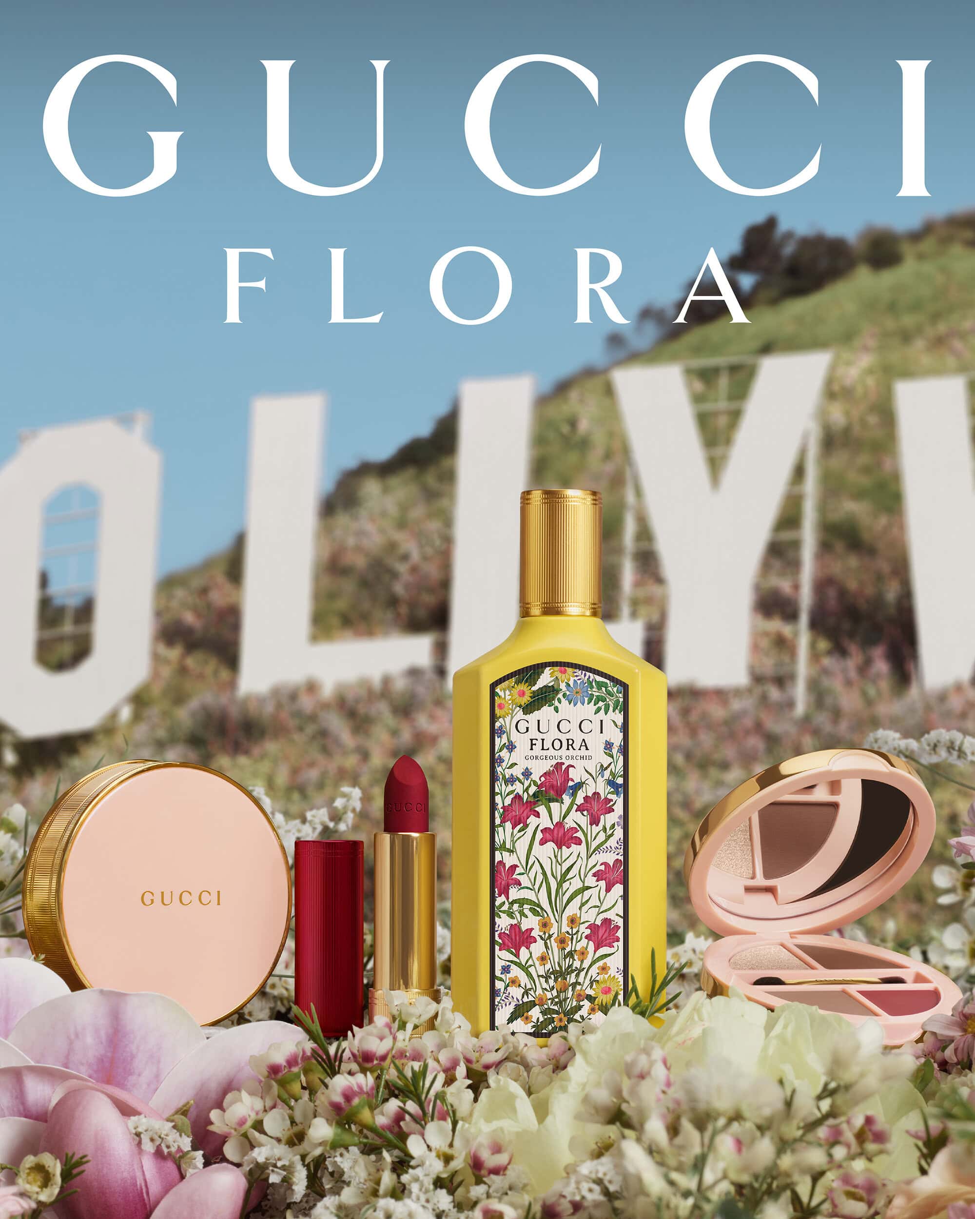 Cosmetic products, including Gucci Flora perfume, lipstick, and compacts, are displayed with the Hollywood sign in the background.