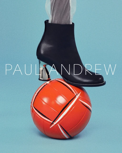 Fashion still life shot featuring a black leather heeled boot with a silver heel atop an orange and white volleyball against a light blue background.