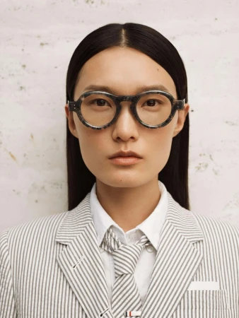 Model wearing round tortoiseshell glasses and striped suit for Thom Browne Eyewear Spring 2024 campaign
