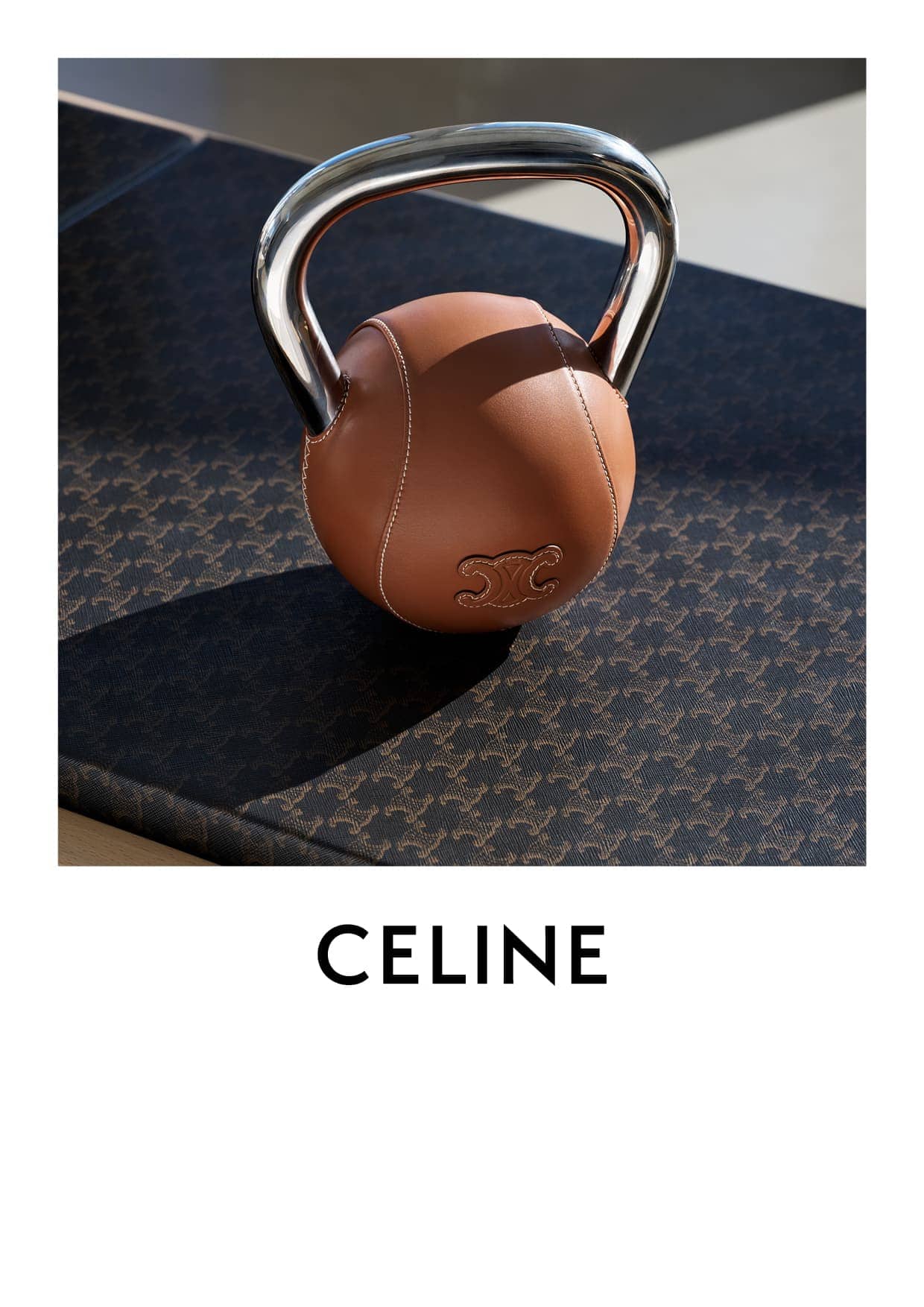 A leather kettlebell with a chrome handle rests on a patterned mat. The brand name CELINE is displayed in bold, sans-serif font.