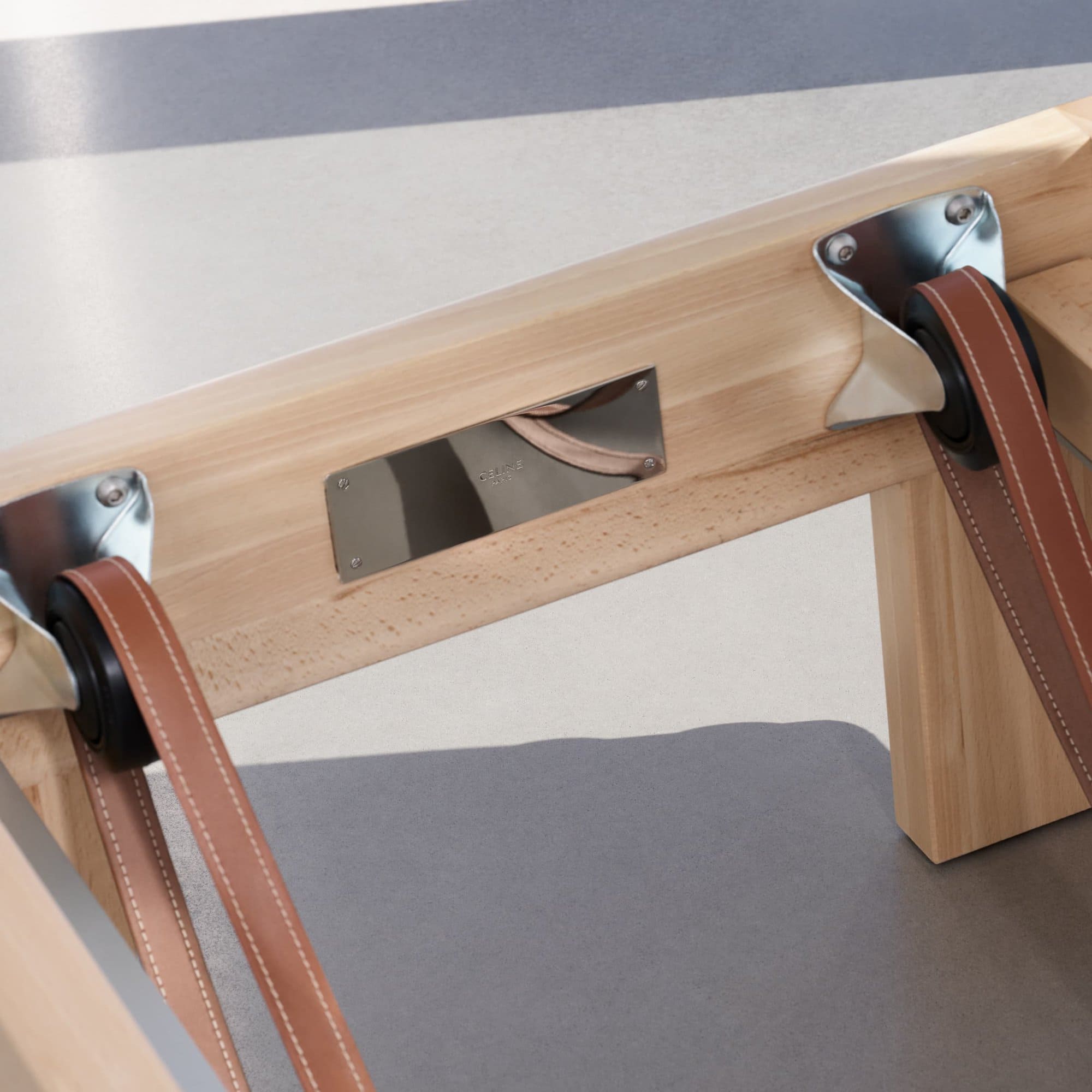 Close-up shot of a wooden reformer pilates machine with leather straps and chrome hardware in a minimalist studio setting.