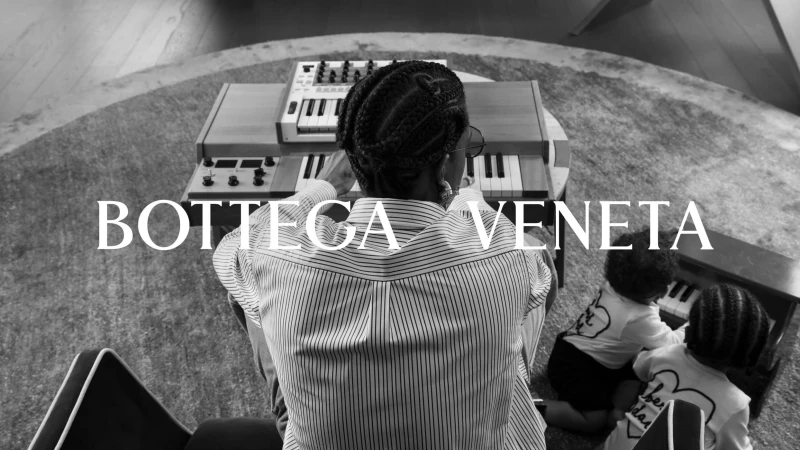 Striking black and white image of a woman and two children at musical keyboards, accentuated by 'Bottega Veneta' text overlay.