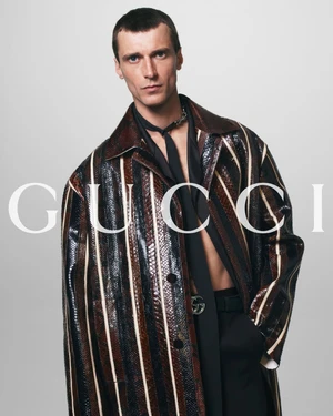 Male model in a striped textured coat and dark necktie against a plain grey background