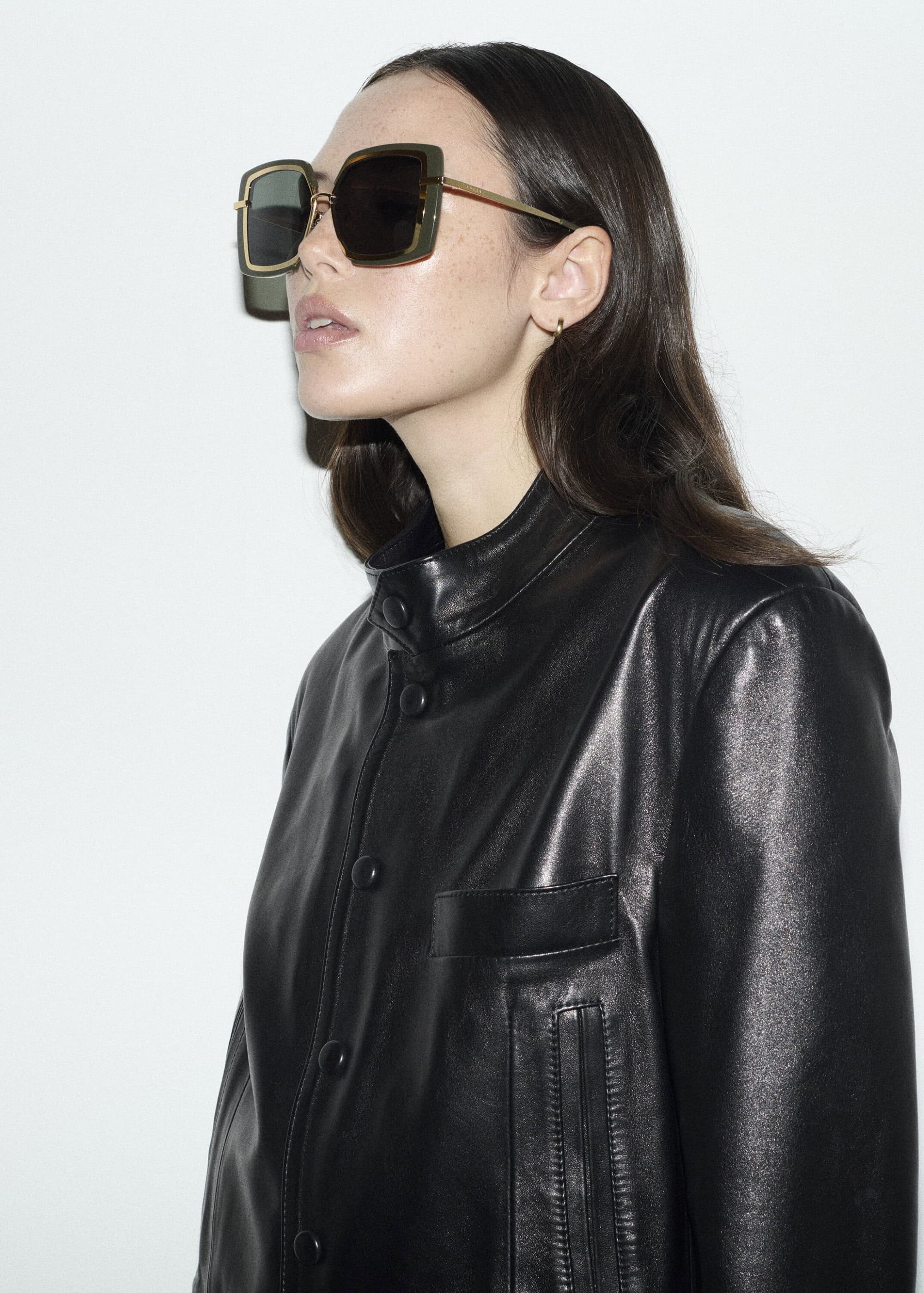 Model wearing large square sunglasses and a black leather jacket against a white background for Edera