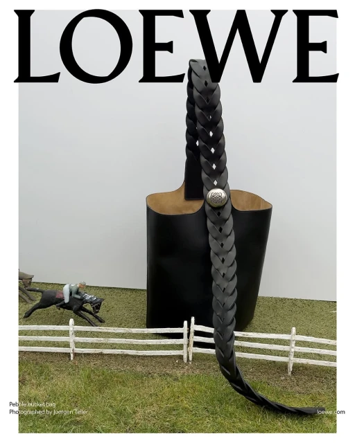 Loewe handbag with braided strap, studio shot with horse and rider miniature model on artificial grass, white background, minimalist.