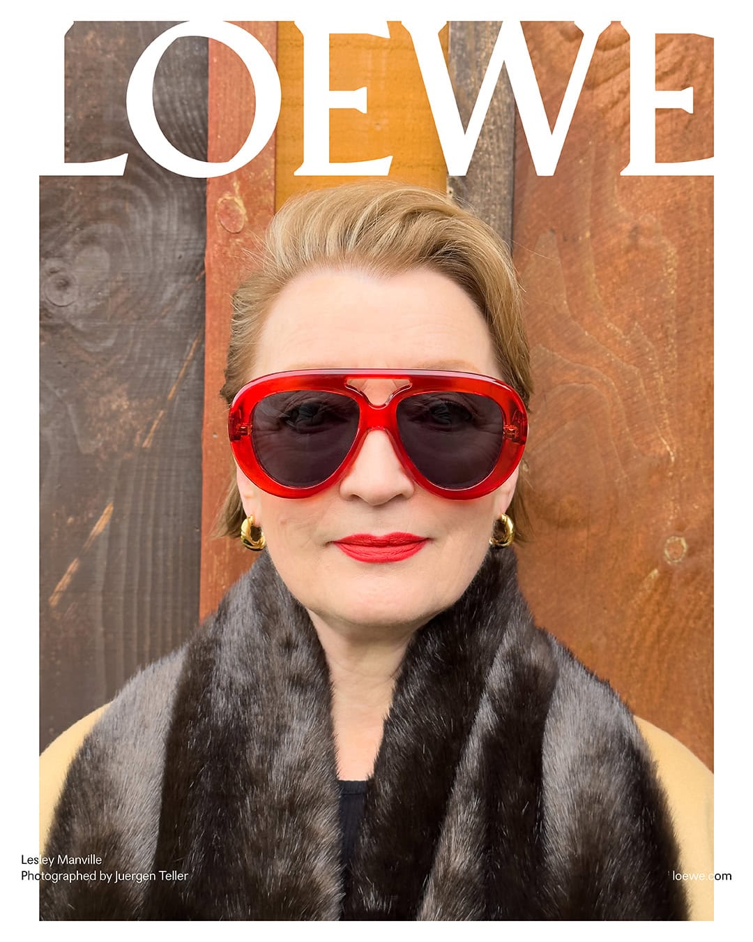 Close-up of mature woman with red lipstick and oversized sunglasses, posing against wooden background with 'LOEWE' text.