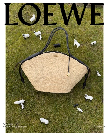 Loewe basket bag in a field of grass surrounded by small toy sheep, top-down shot with the brand name displayed above.