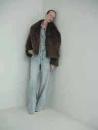 Model Lili Sumner wearing a fluffy brown jacket and light denim outfit against a grey studio corner for Sass & Bide
