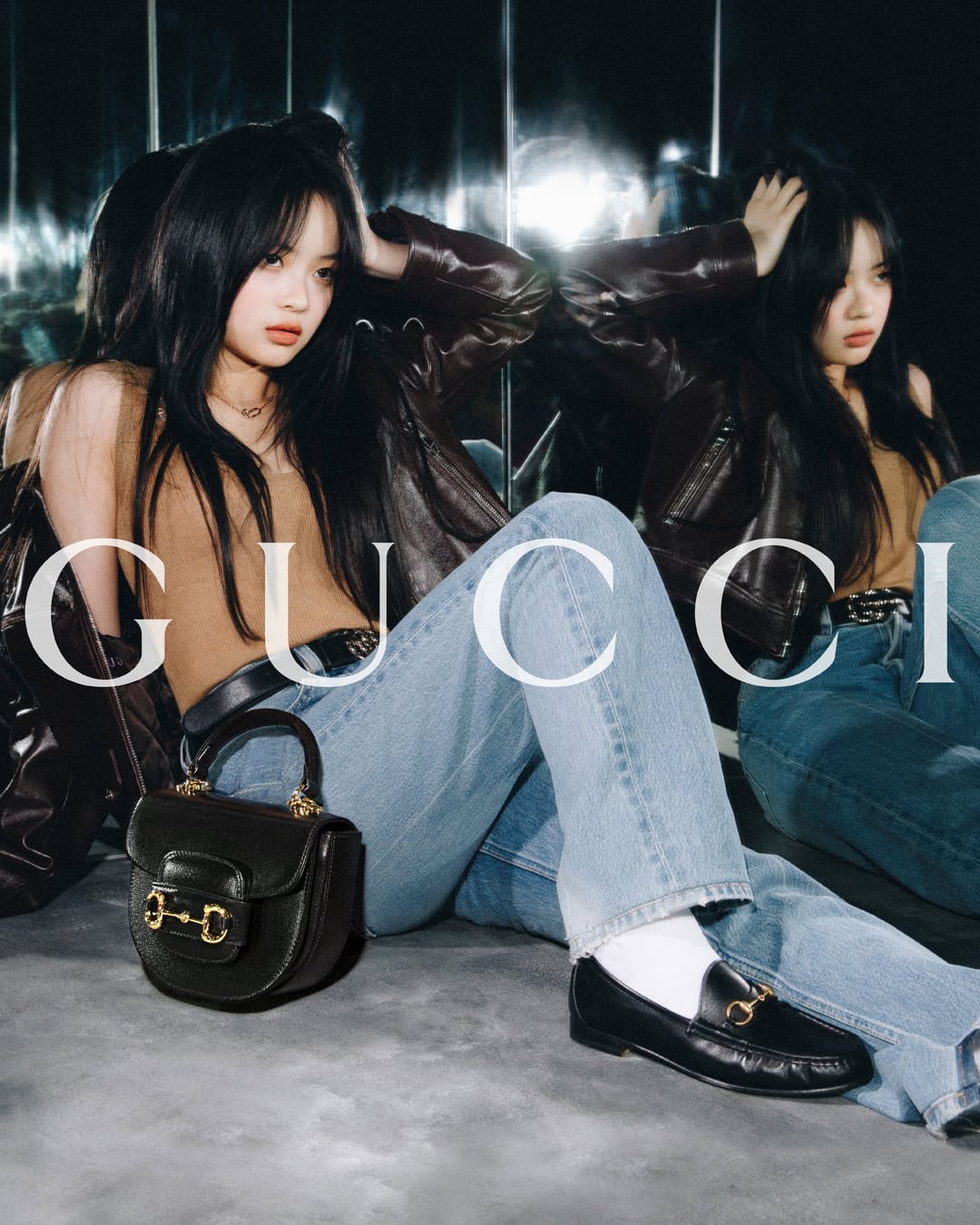 A young woman in casual clothing poses with a black Gucci handbag and loafers, sitting in front of a mirrored wall with text overlay.