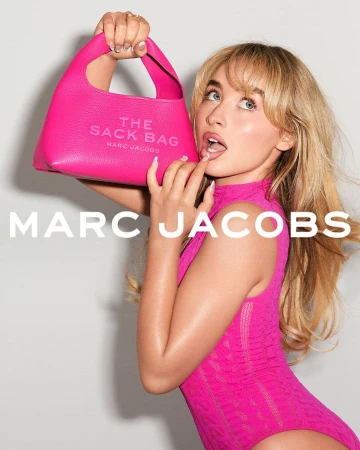 Fashion shot of a woman holding a pink Marc Jacobs purse. The young adult female model has blonde hair and wears a pink outfit.