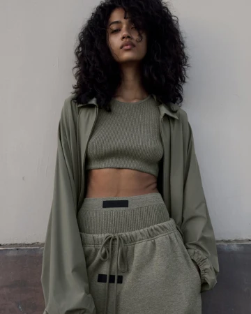 Woman with long dark curly hair wearing olive green matching ribbed top and sweatpants for Fear of God.