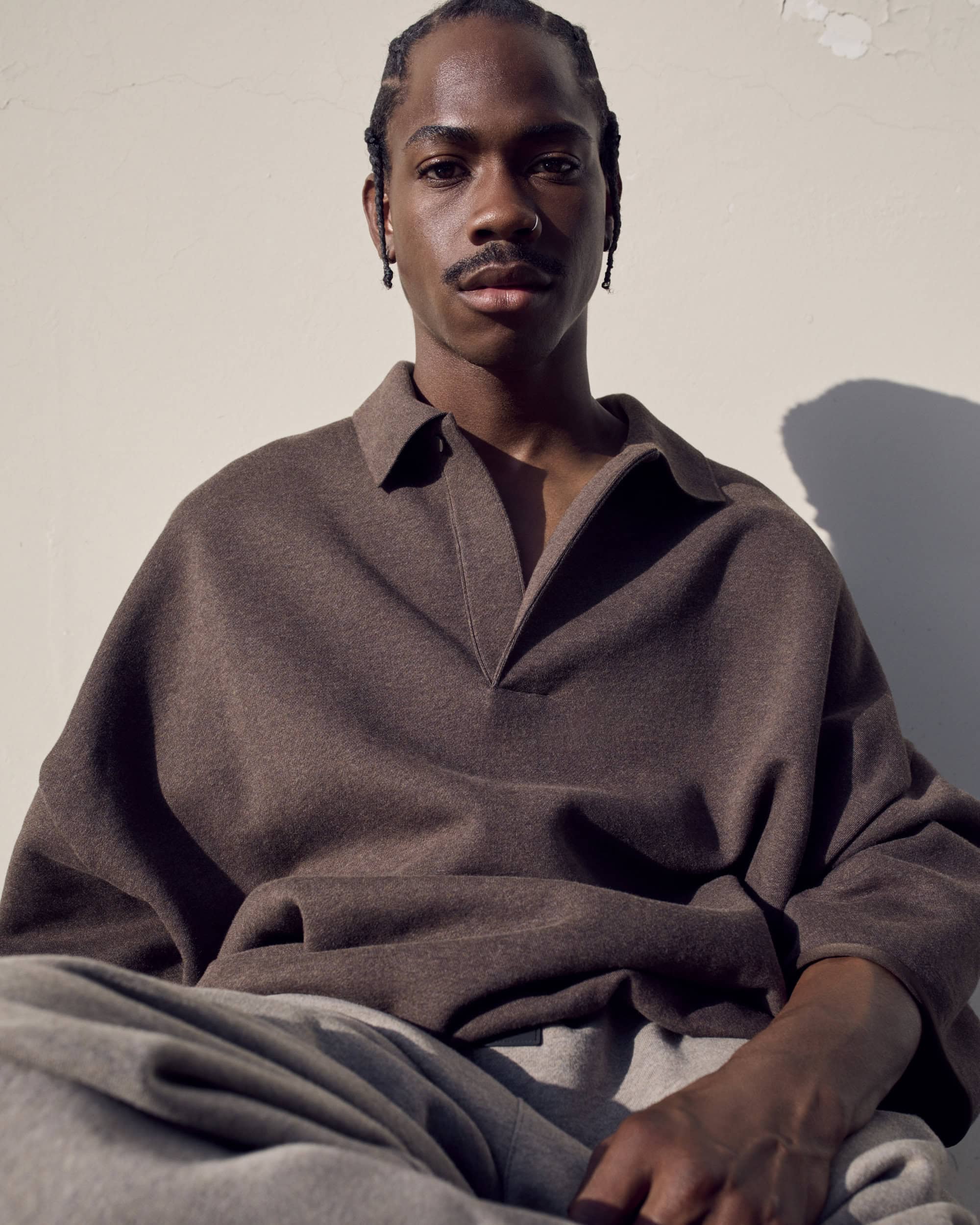 Man wearing a brown polo shirt posing against a plain background for Fear of God Summer 2024 collection