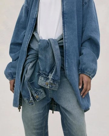 Close up of person wearing a blue denim jacket over a white shirt with a matching denim jacket tied around their waist.