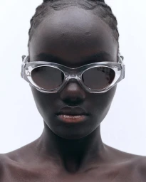 Close-up portrait of a model wearing clear sunglasses against a plain white background for 13 09 SR