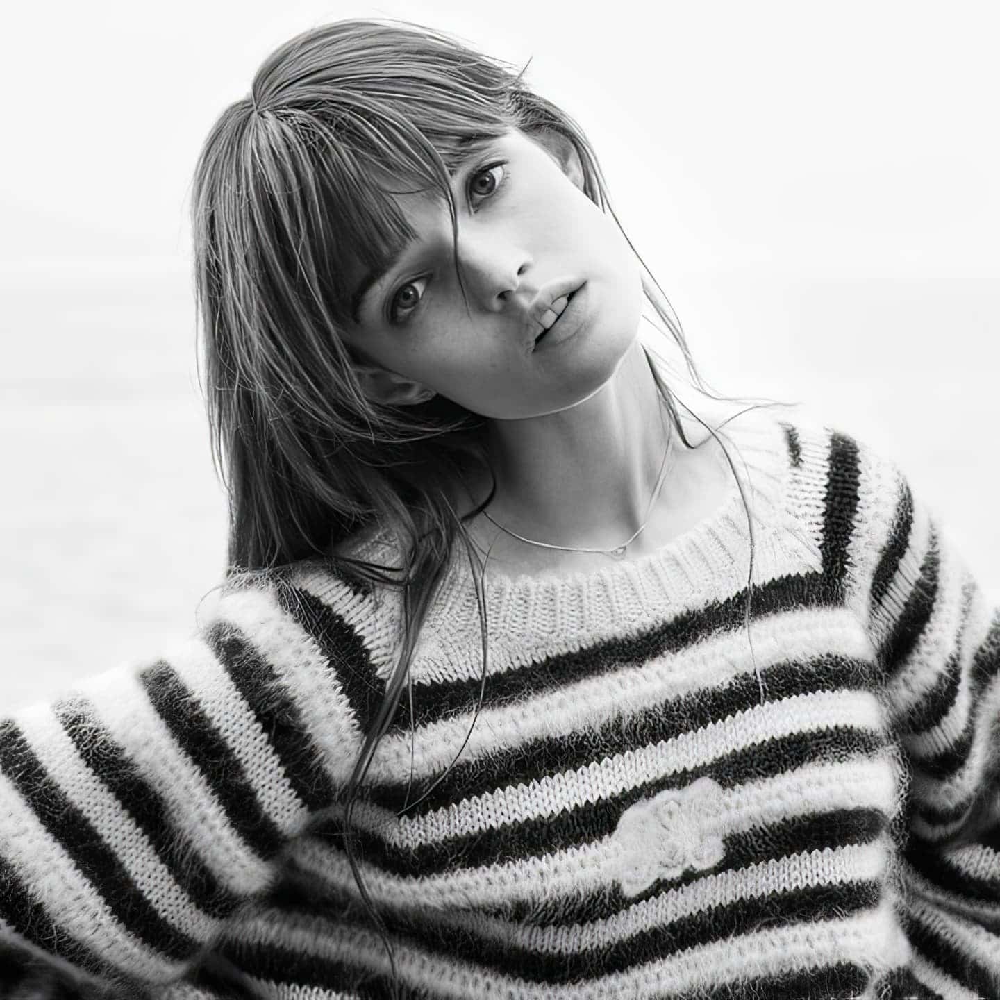 Black and white portrait of an adult female wearing a striped sweater against an indistinct light background.