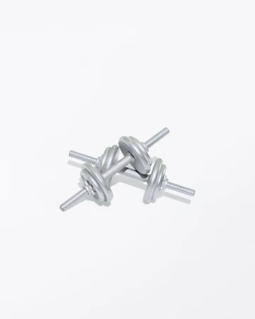 Close-up of two silver dumbbells overlapping on a white surface, ideal for strength training and fitness workouts at the gym.