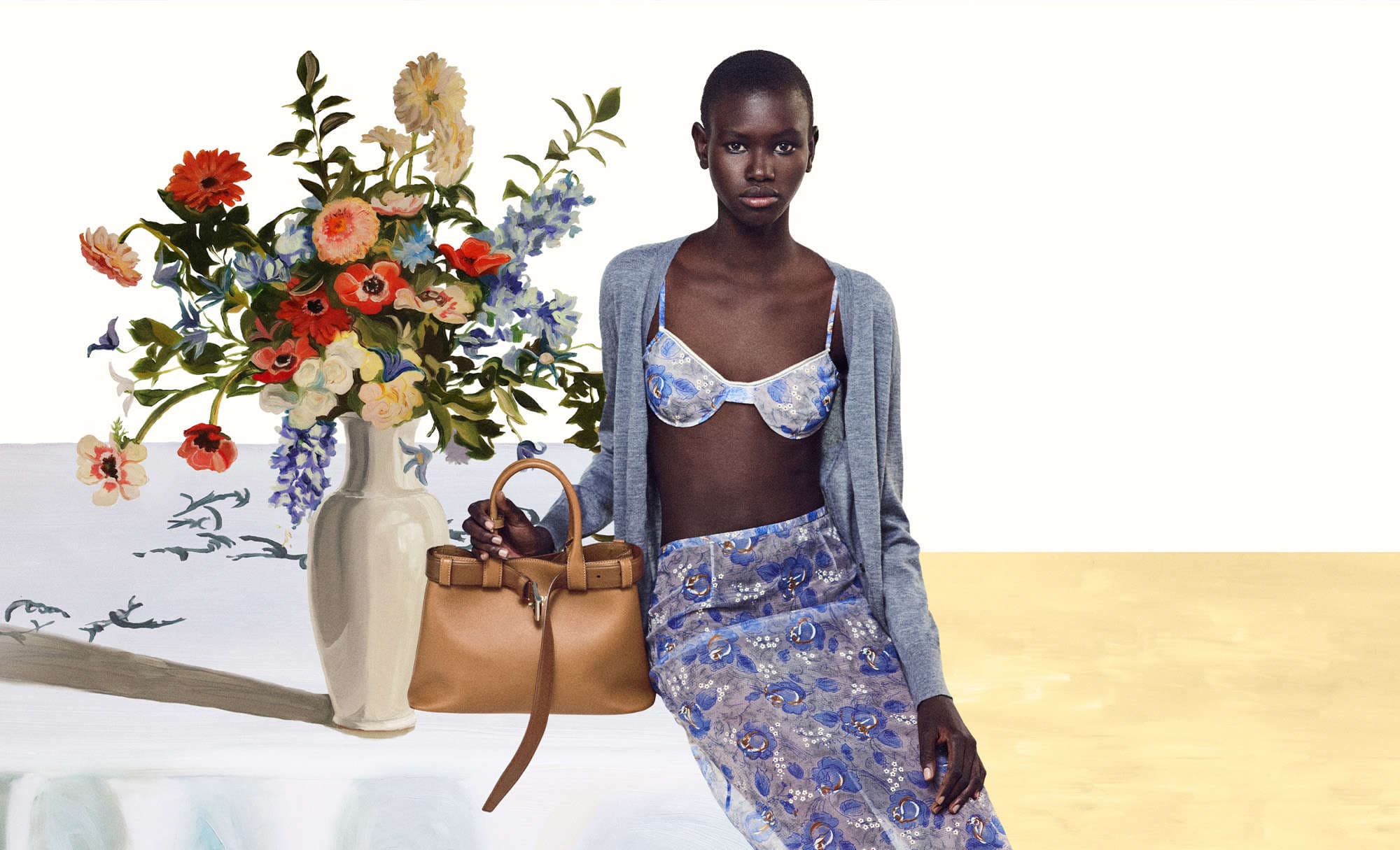 Elegant woman in bra top and skirt poses with a handbag and vase of flowers in a fashion studio setting with bright, balanced lighting.
