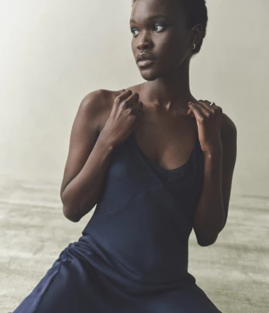 Model with short dark hair wearing a dark slip dress against a pale neutral background for Rue Sophie.
