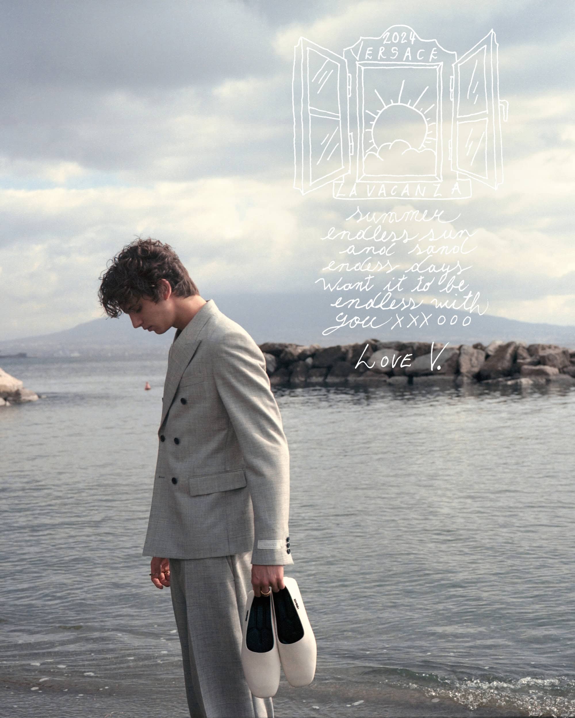 Man in suit stands on beach, holding shoes. Features coastal view, soft light, sketched text overlay, fashion, and seaside mood.