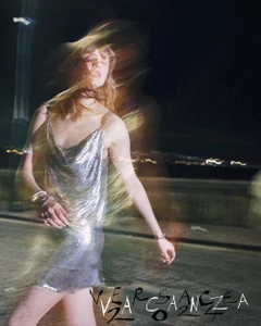 Model in a silver chainmail dress captured with motion blur against a dark nighttime street background