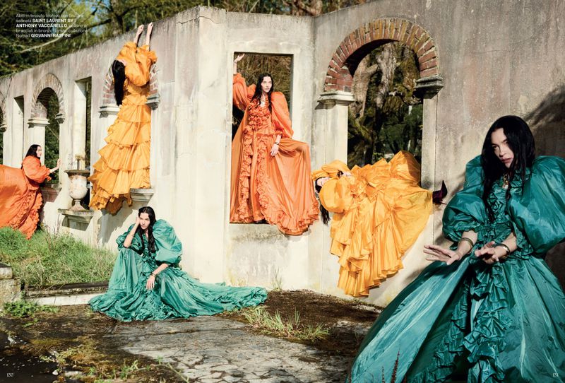 Multiple models pose in a surreal outdoor fashion editorial, wearing ruffled gowns within and around weathered architectural ruins.
