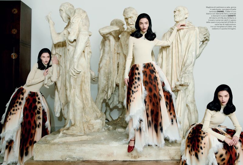 A woman in a leopard-print skirt poses with sculptures in a fashion editorial, showcasing a blend of modern fashion and classical art.