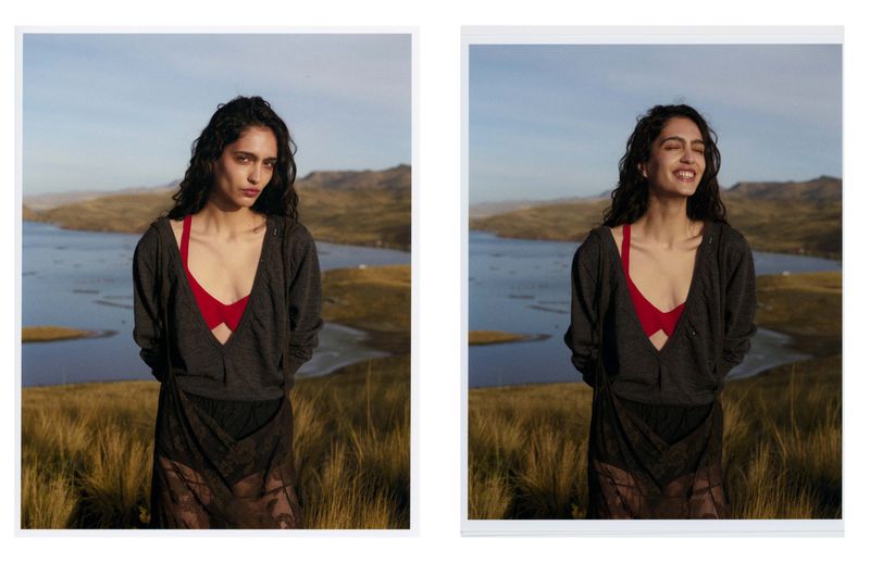 Woman in grey cardigan and red bra poses with a sad face and a happy face in a mountain landscape with lake and tall grass.