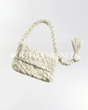 White woven leather Bottega Veneta handbag floating against a plain white background with bold typographic branding