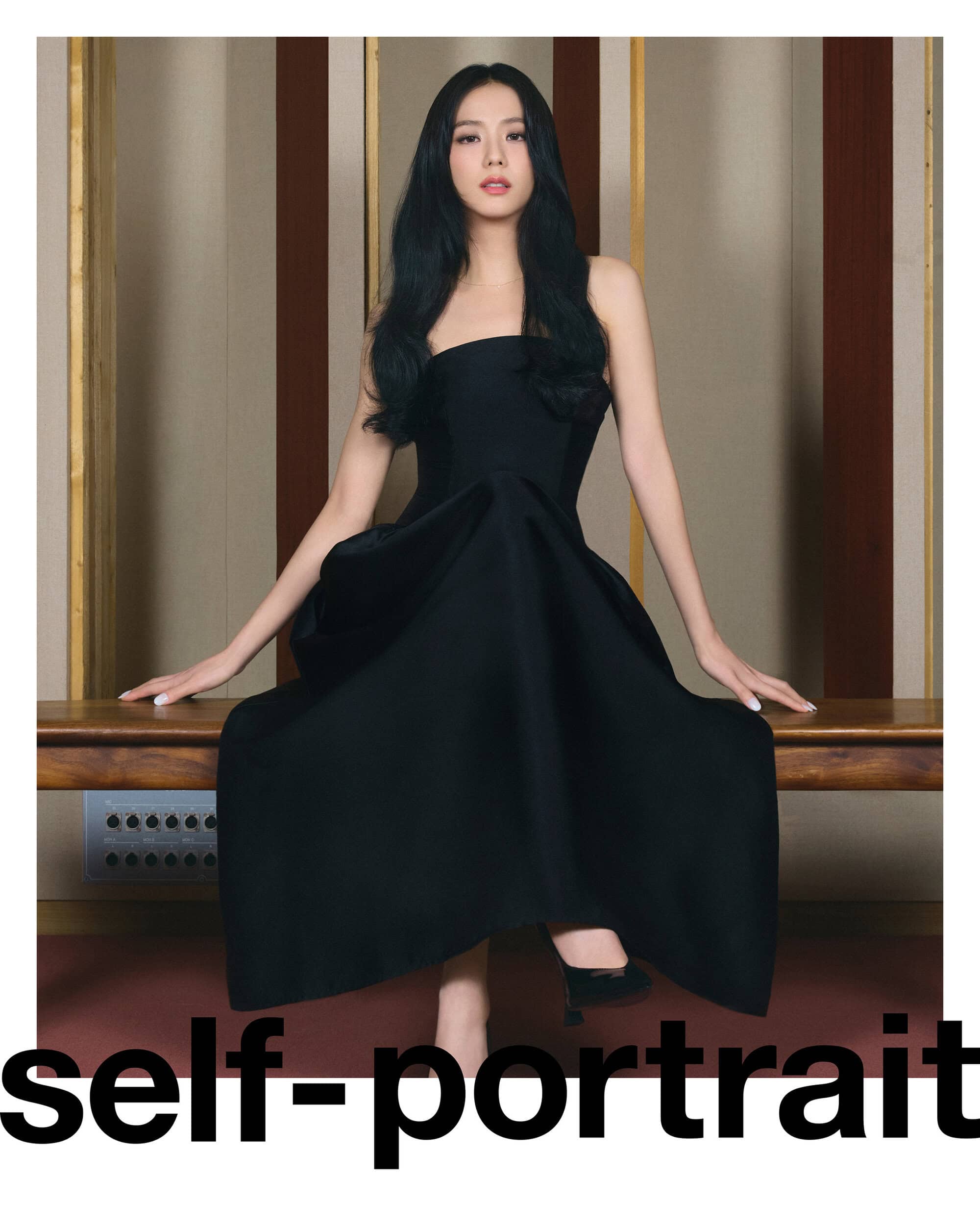 Elegant Asian woman in strapless black gown sits on a wooden bench against a paneled wall, complemented by black heels and soft lighting.