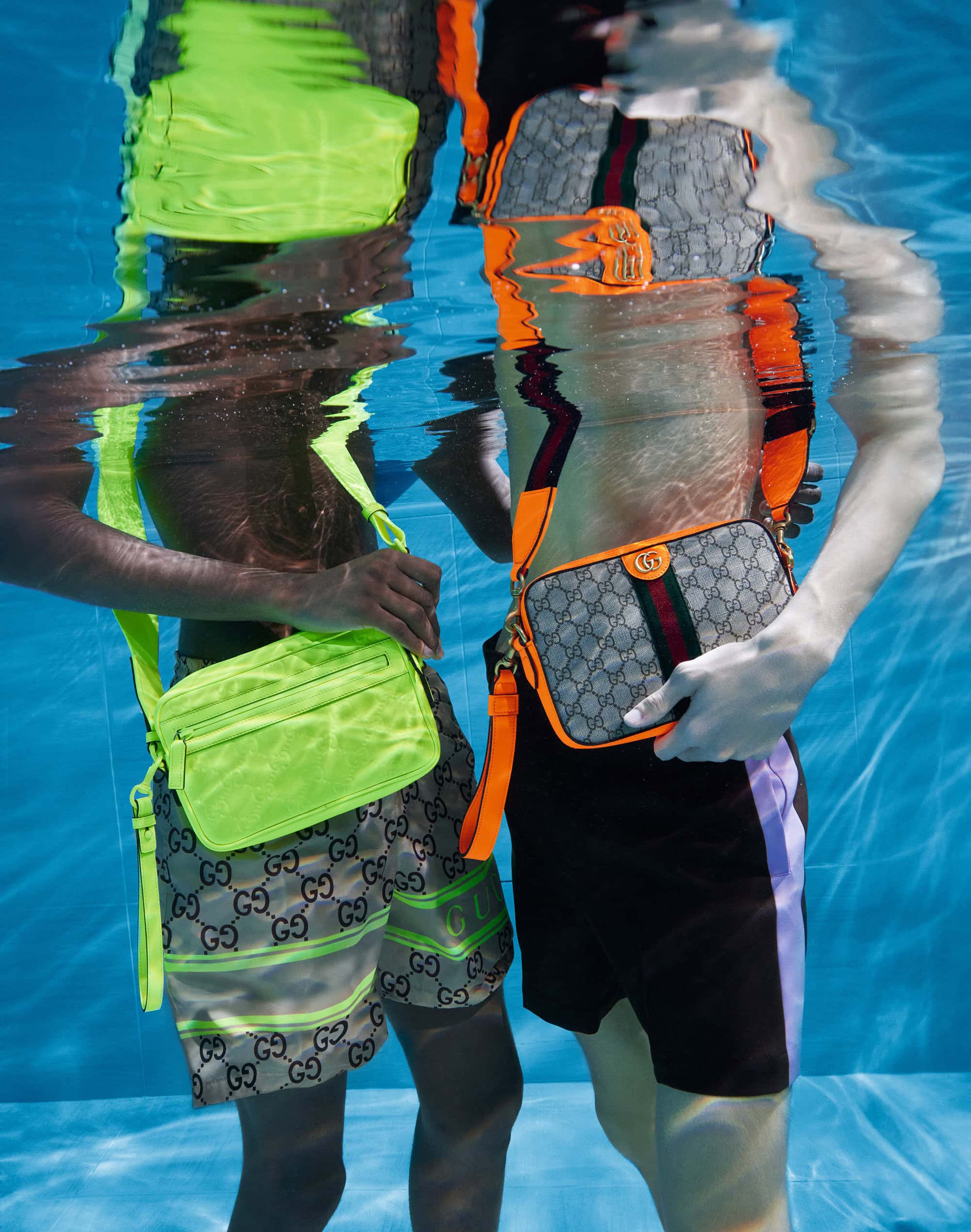 Two people in a pool underwater, showcasing Gucci bags and matching Gucci patterned swimwear. The bags are bright neon and muted grey.