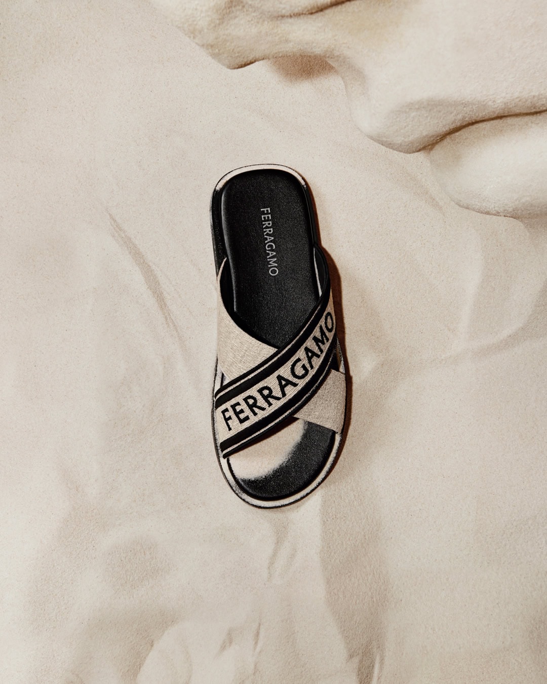 Ferragamo slide sandal on a white textile background in a neutral colour palette, highlighting fashion footwear.