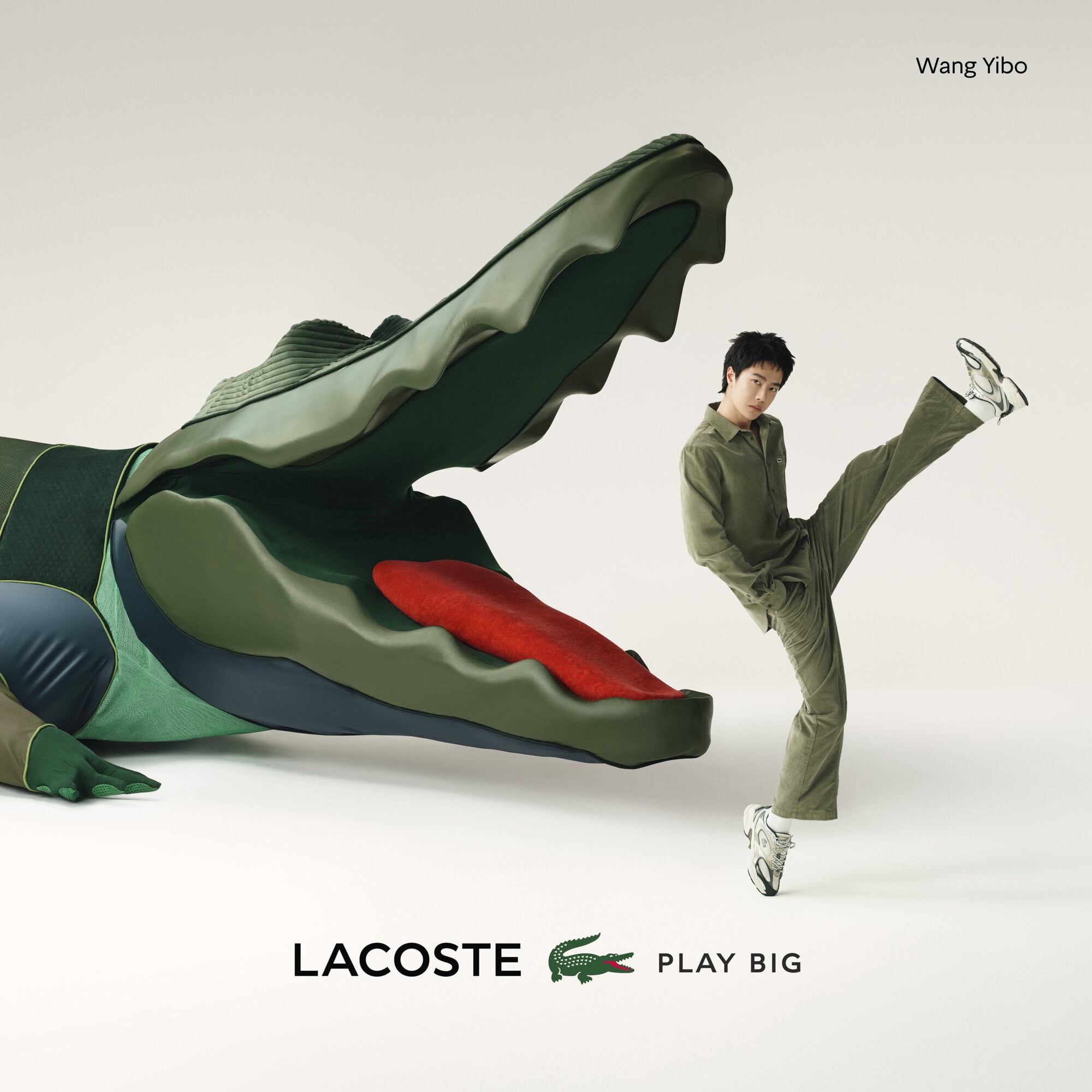 Asian male model poses with a giant Lacoste crocodile prop in a studio, showcasing a sporty look and the brand's playful theme.
