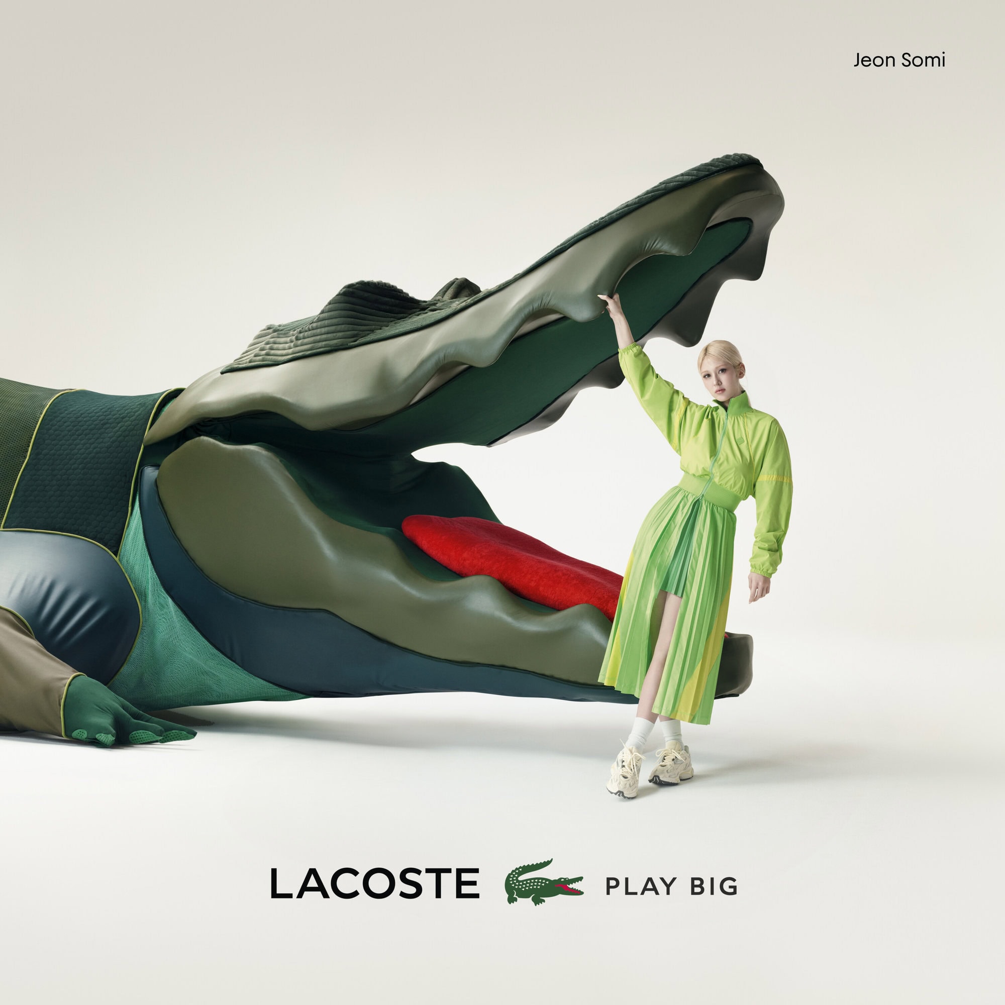 A woman in a green outfit stands next to a very large, green Lacoste alligator head, with the Lacoste logo in the lower corner.