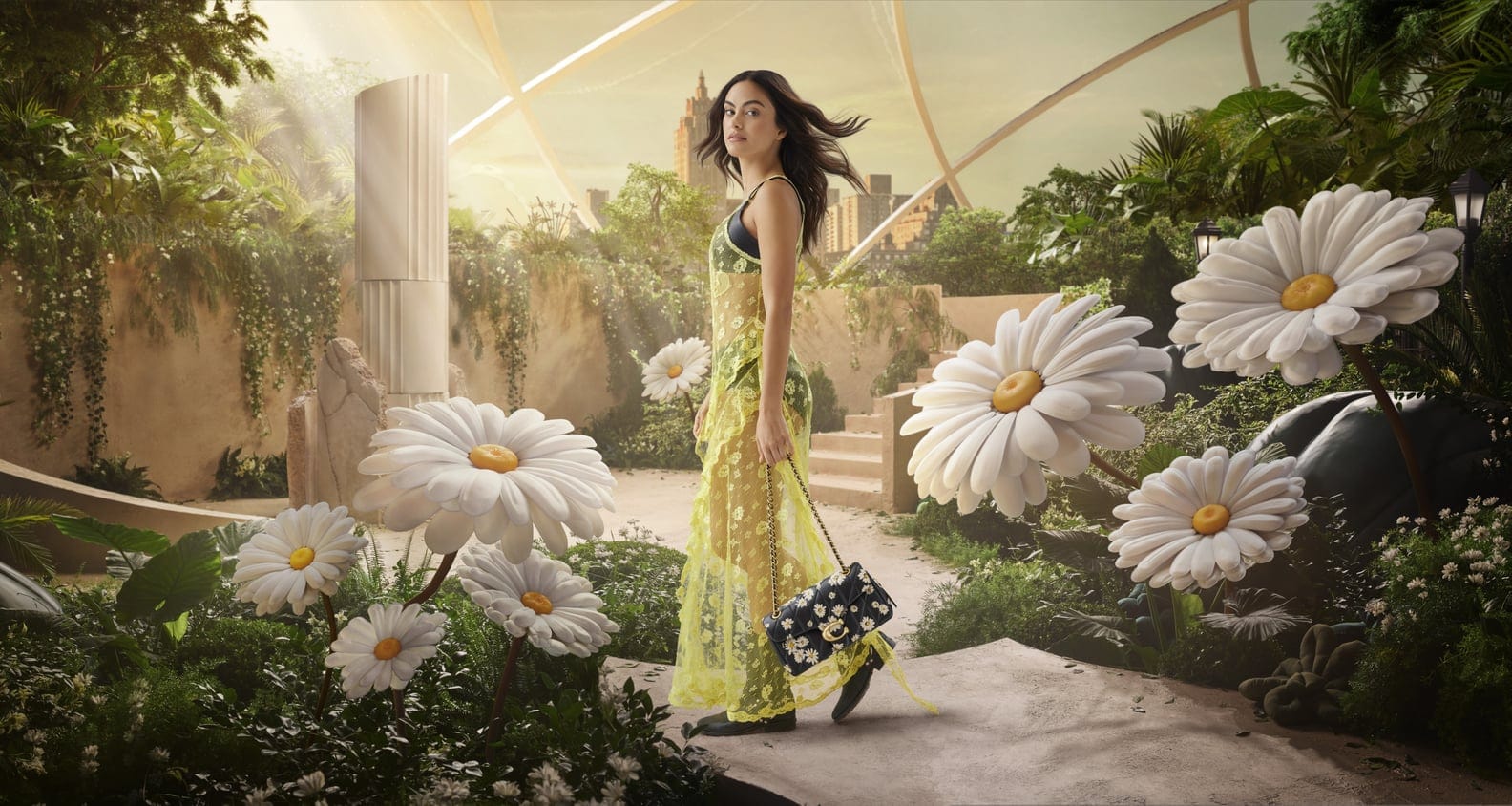 A woman in a floral dress stands on a stone path, surrounded by oversized daisies in an indoor garden with cityscape backdrop.