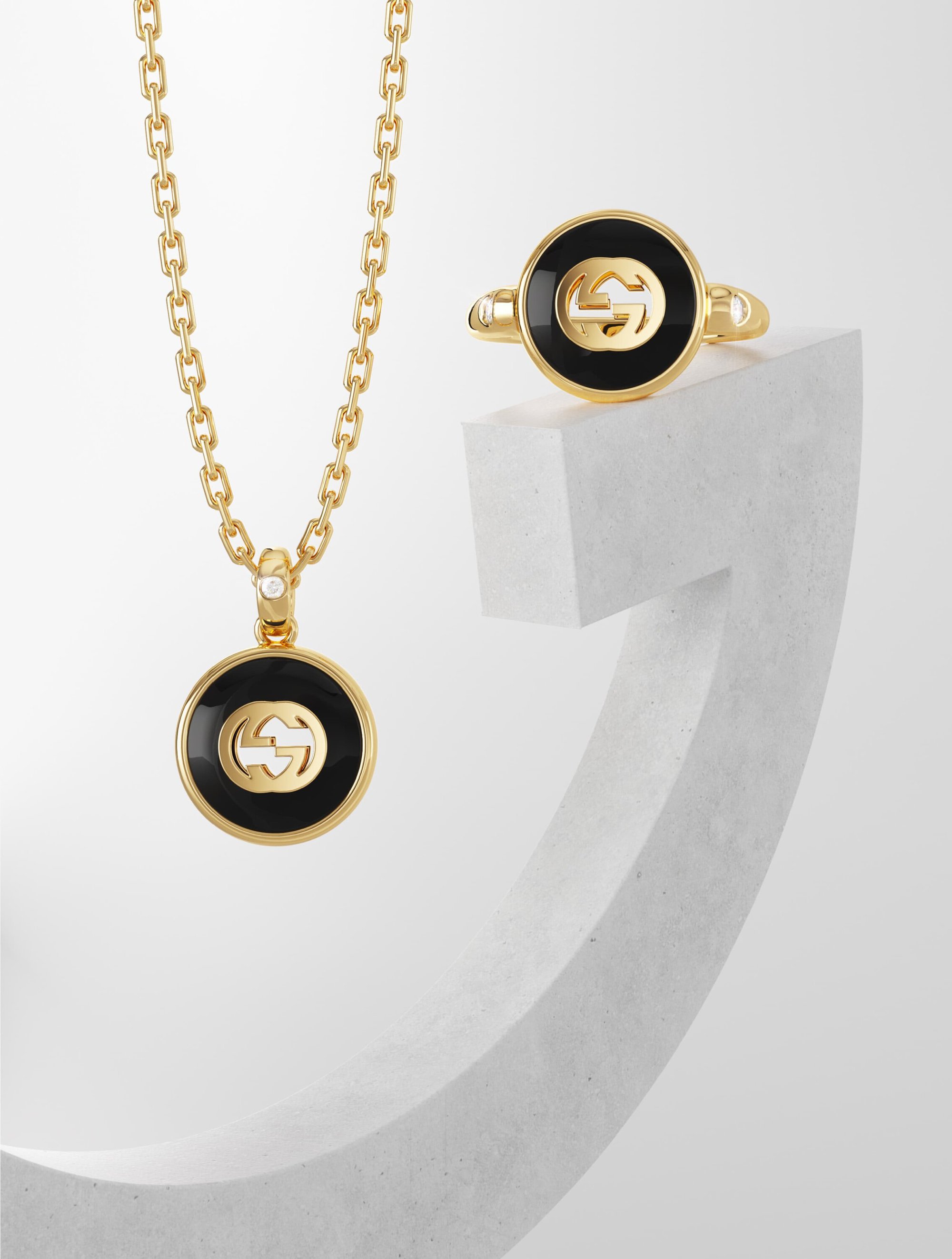 Elegant studio shot of a gold Gucci necklace and ring set against a clean white backdrop, ideal for luxury fashion or jewelry advertising.