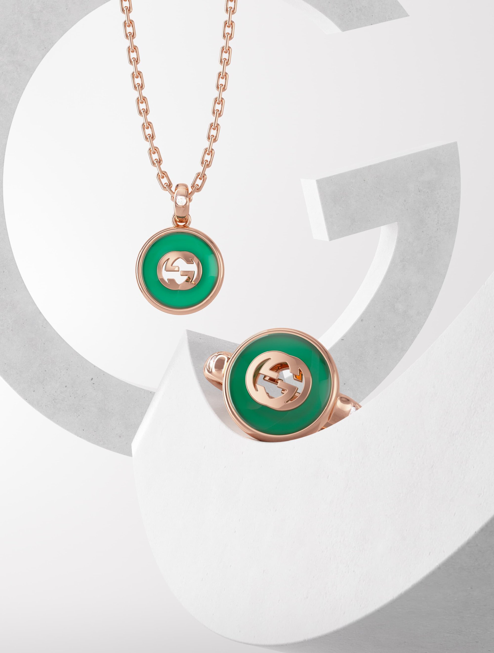 Elegant rose gold chain necklace and matching ring on a white abstract 'G' backdrop, perfect for a fashion jewelry product shot.